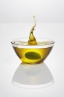 Olive falling into glass dish — Stock Photo