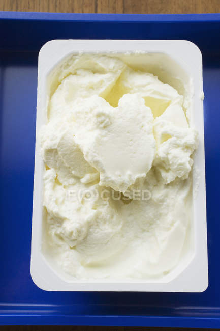 Quark in opened plastic packaging on a blue dish — Stock Photo