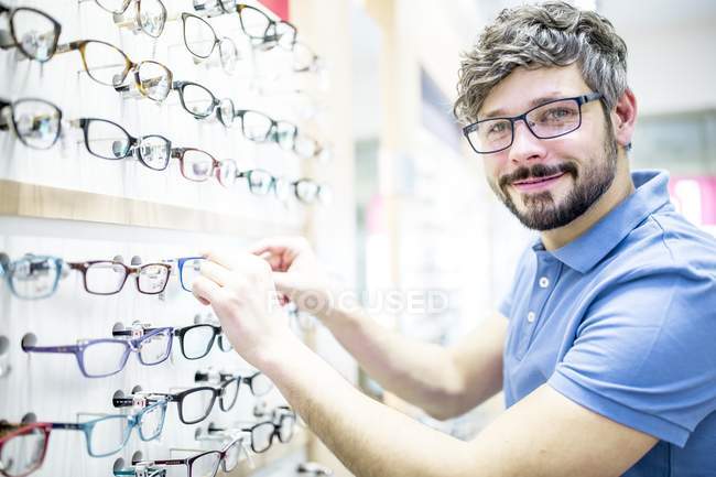 Man at glasses rack in optometrist shop. — Stock Photo