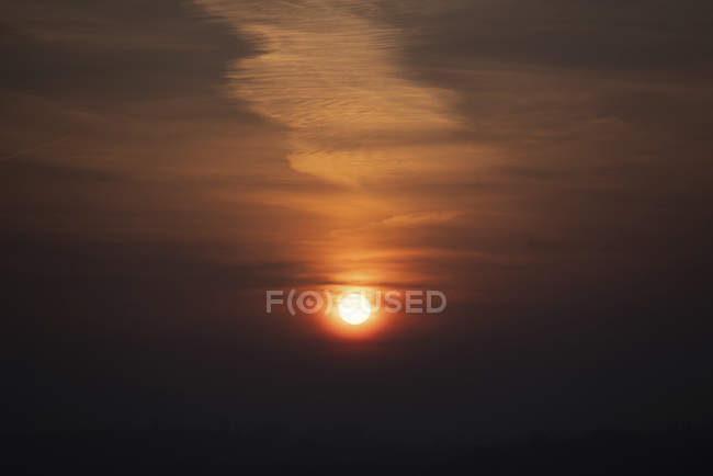Scenic cloudscape on dark sky with glowing sun at sunset. — Stock Photo
