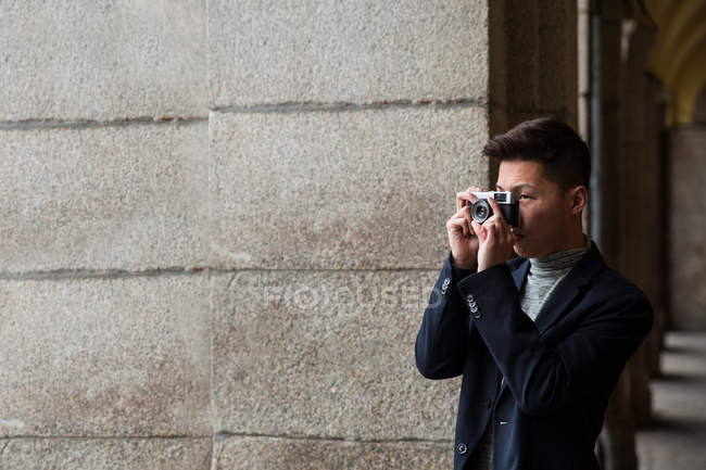 Jeune Chinois décontracté prenant des photos avec un appareil photo vintage à Madrid, Espagne — Photo de stock