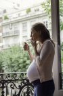 Pregnant woman smoking cigarette on the balcony — Stock Photo