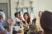 Friends watching happy woman with fireworks birthday cake at restaurant table — Stock Photo