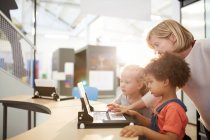 Teacher and schoolgirls using laptop in science center — Stock Photo