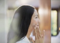Profile young woman applying moisturizer to cheek — Stock Photo