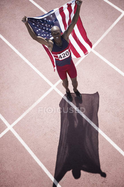 Track and field athlete holding American flag on track — Stock Photo