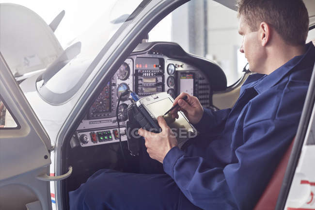 Male engineer checking diagnostics with digital tablet in airplane cockpit — Stock Photo