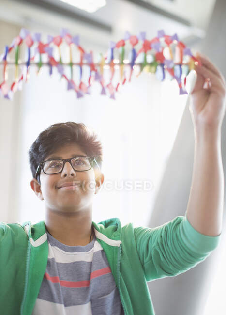Boy student examining DNA model in classroom — Stock Photo