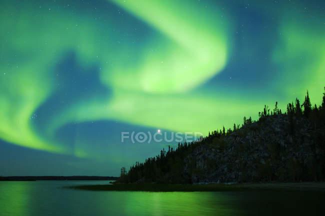 Aurora boreal sobre el lago en el bosque boreal, alrededores de Yellowknife, Territorios del Noroeste, Canadá - foto de stock