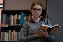 Young woman reading a book in the library — Stock Photo