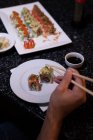 Man picking up sushi with chopsticks in a restaurant — Stock Photo