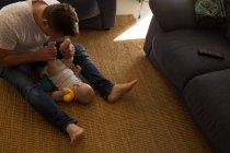 Father playing with his baby boy in living room at home — Stock Photo