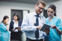 Doctor and nurse discussing over digital tablet in hospital corridor — Stock Photo