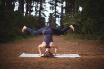 Woman performing yoga in forest on a sunny day — Stock Photo