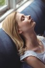 Beautiful woman relaxing on sofa in living room at home — Stock Photo