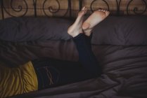 Crossed legs of woman lying on bed in bedroom at home — Stock Photo