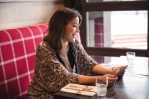 Woman sitting in restaurant and using a digital tablet — Stock Photo