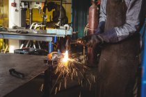 Cropped image of welder welding metal in workshop — Stock Photo