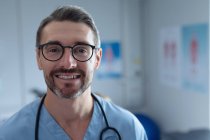 Portrait of mature Caucasian male surgeon with stethoscope around the neck looking at camera in hospital — Stock Photo