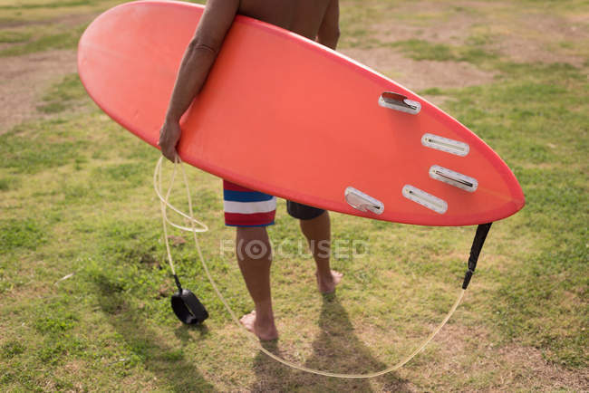 Male surfer holding surfboard leash at beach — Stock Photo