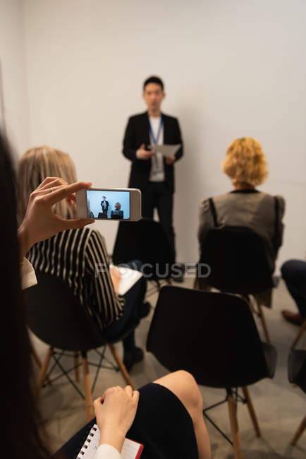 Executive taking photo with mobile phone in office — Stock Photo