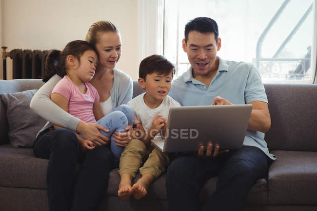 Smiling parents and kids using laptop in living room at home — Stock Photo