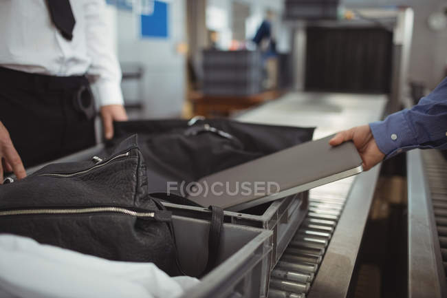 Man putting laptop into tray for security check at airport — Stock Photo