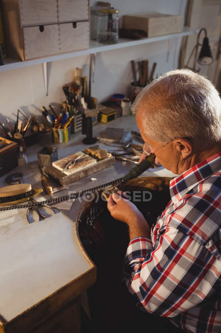 Attentive goldsmith using hand piece machine in workshop — Stock Photo