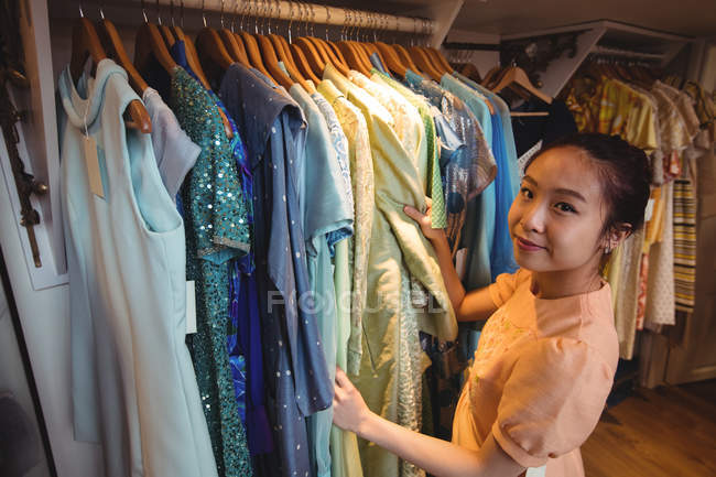 Woman selecting a clothes from hangers at boutique store — Stock Photo
