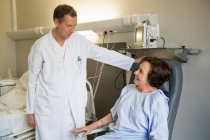 Male doctor assisting female patient in hospital — Stock Photo