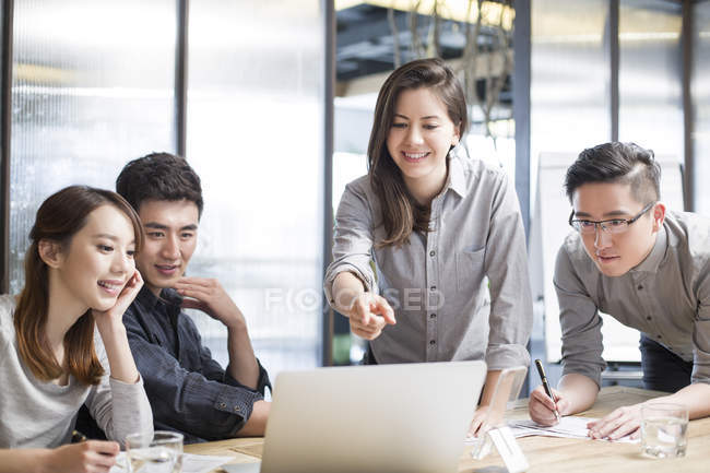 Chinese co-workers sitting at meeting room with laptop — Stock Photo