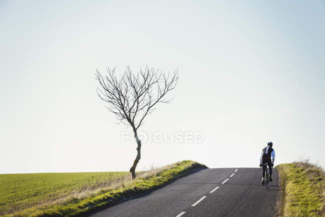 Cyclist pedaling along country road — Stock Photo