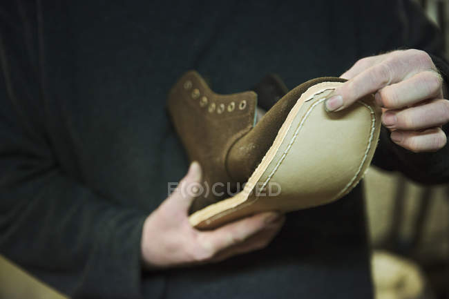 Worker attaching sole to leather boot. — Stock Photo