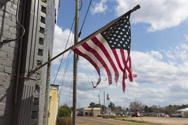 Tattered American flag flying on a building on Main Street. — Stock Photo