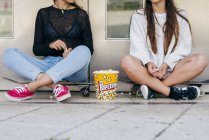 Stylish teens with popcorn on skates — Stock Photo