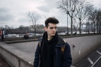 Thoughtful young man in glasses posing on background of asphalt road — Stock Photo