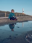 Boy at beacon reflecting in puddle — Stock Photo