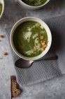 Cuenco con sopa de espinacas, col rizada y crema de hinojo en superficie gris - foto de stock