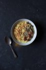 Oatmeal porridge with turmeric in bowl on dark background — Stock Photo