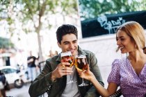 Cheerful young attractive couple enjoying refreshing drinks in city cafe — Stock Photo