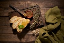 Top view composition of delicious sliced homemade bread with aromatic herbs and sweet yellow fruit jam on rustic wooden table — Stock Photo