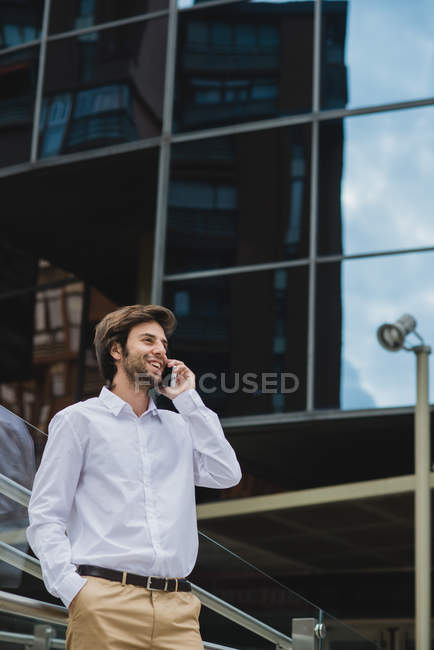 Portrait of smiling businessman in talking on smartphone at downtown urban scene — Stock Photo