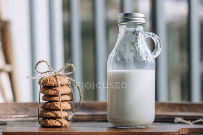 Bouteille de lait et biscuits sur table en bois . — Photo de stock