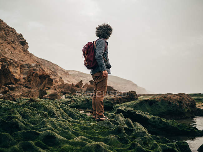 Tourist standing on green stone at ocean — Stock Photo