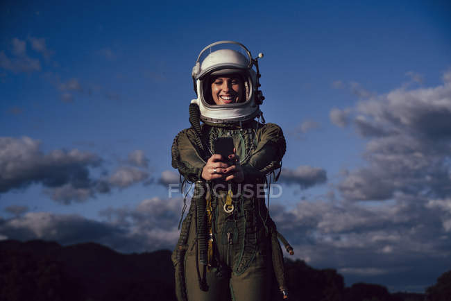 Smiling female astronaut taking selfie mobile phone in evening nature — Stock Photo