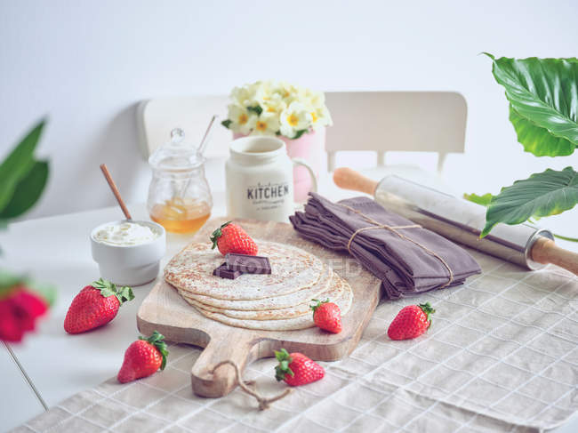 Frühstück mit Pfannkuchen und Erdbeeren auf Küchentisch mit Blumen — Stockfoto