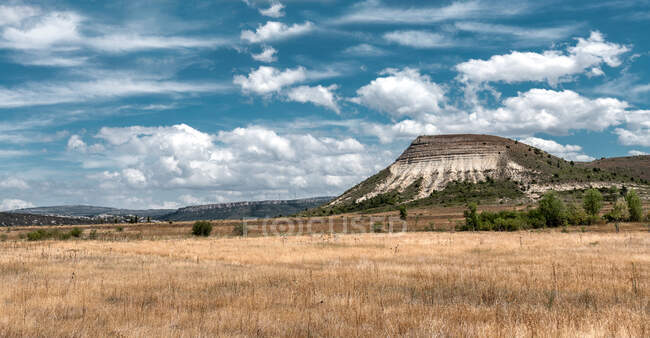 Spacious field with dry grass and hills behind — Stock Photo
