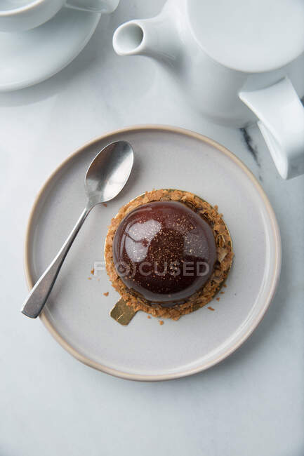 Haute cuisine confectionery product of creamy mousse in chocolate decorated with cereals on plate with spoon — Stock Photo