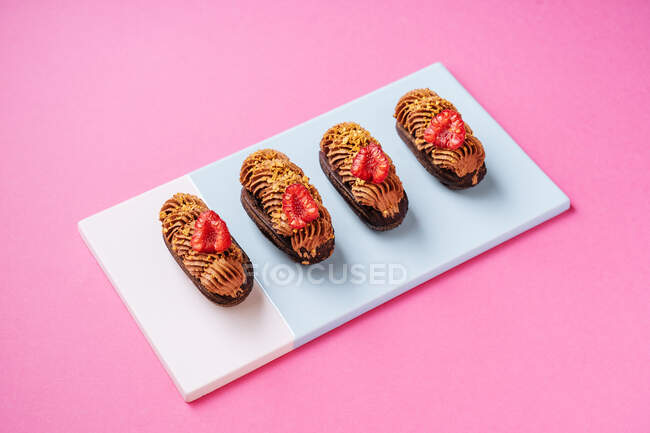 Chocolate eclairs with fresh raspberries — Stock Photo