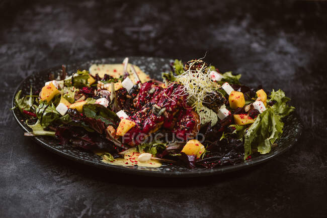 Plate with tasty vegetarian Indonesian salad with fresh mango and cashew cheese slices near soybeans and condiments covered with basil vinaigrette — Stock Photo